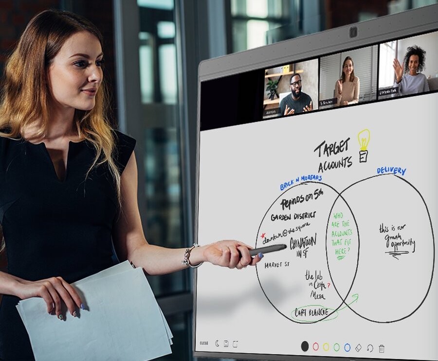 A woman presenting in a video conference meeting while utilizing an interactive whiteboard.