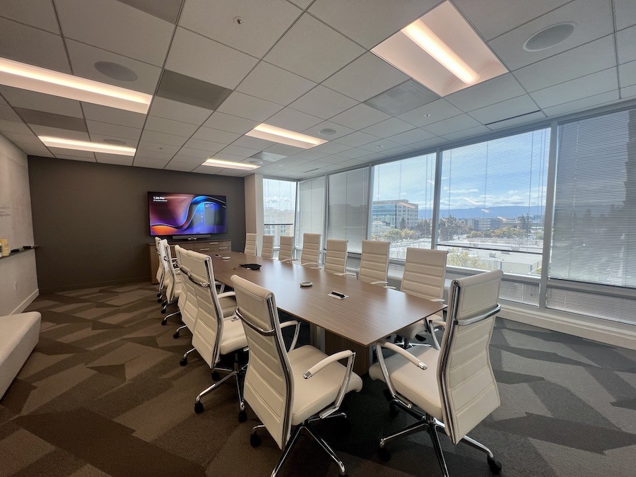 A modern Santa Clara meeting room with a large display screen and conference table equipped with an advanced conference room camera in the front. 