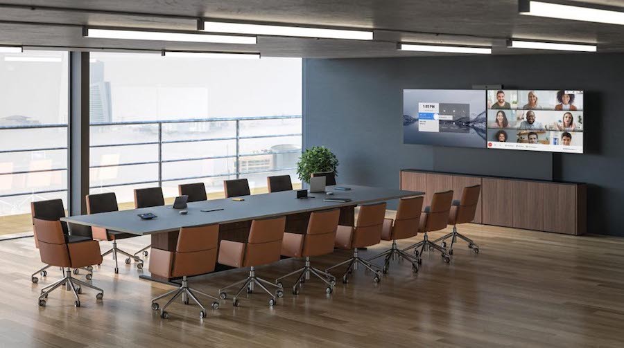 A modern meeting room with a large conference table and two large displays in the front of the room.