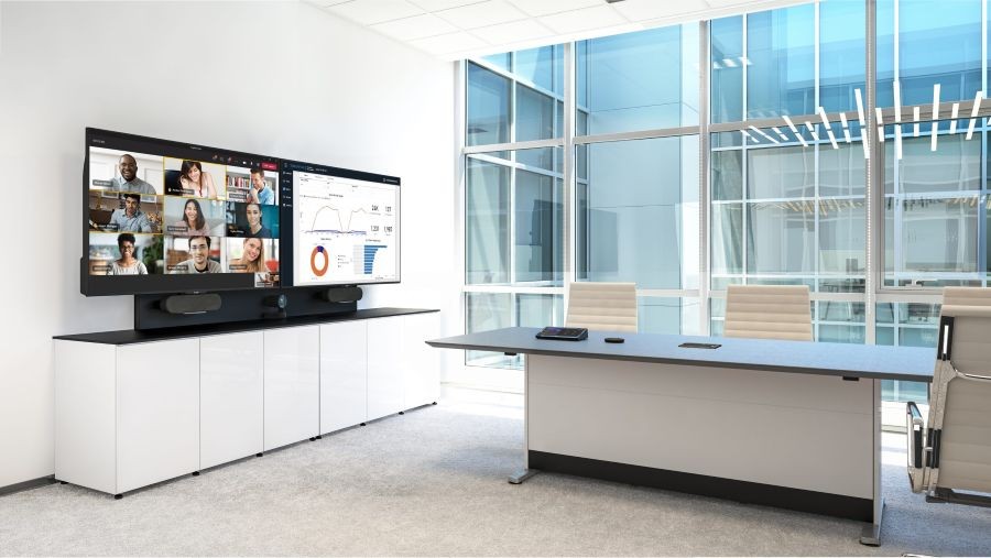 A video conference meeting room with two displays and large glass windows.