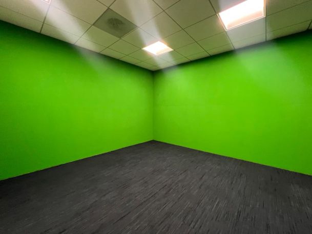 Empty room with bright green walls, suited for green screen or video production use.